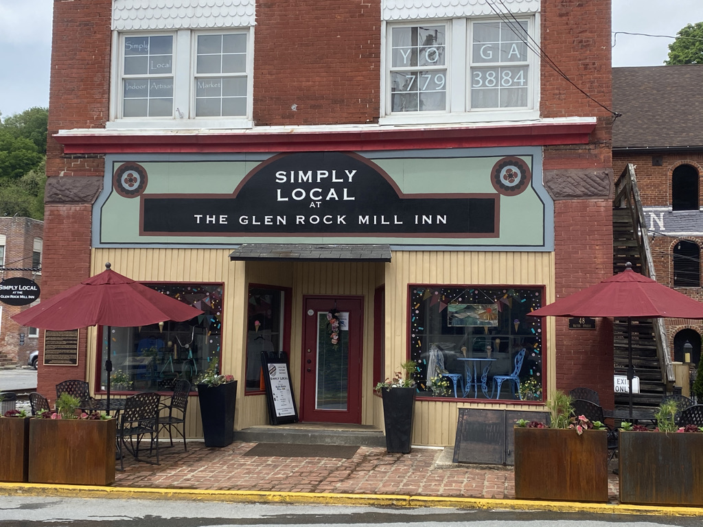 brick building facade of Simply Local at the Glen Rock Mill Inn with table and chairs on the sidewalk